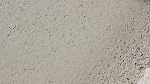Worker smoothing fresh concrete with trowel close-up footage of a construction worker using a long-handled trowel to level and smooth a freshly.