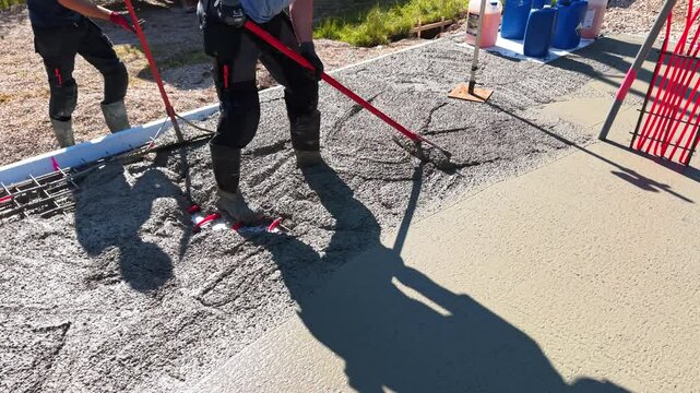 Pouring concrete over underfloor heating system &ndash; construction process Video of a construction worker in rubber boots pouring concrete over red underfloor.