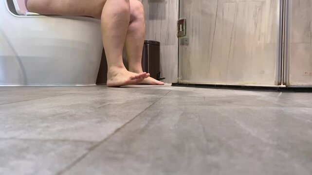 adult woman legs cellulite old age incontinence diarrhea sitting on the toilet slapping feet on the floor sitting for a long time Girl walk to bathroom, sit down on toilet. Put off underwear. 