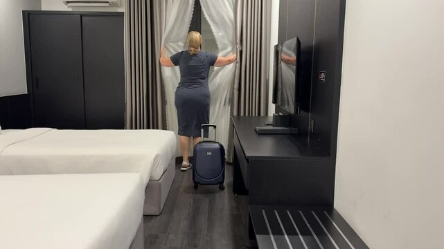 room without window hotel. an adult woman with a suitcase enters a hotel a dark room a woman opens the tulle there is no exit to the street the window opens into the wall of a neighboring house shock