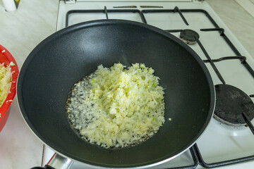 shredded cabbage cooking in a wok on a gas stove