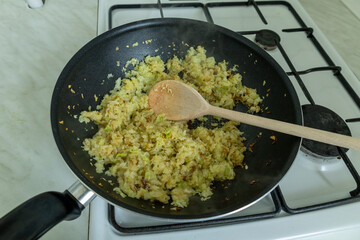 caramelized cabbage and wooden spoon in a wok on a gas stove