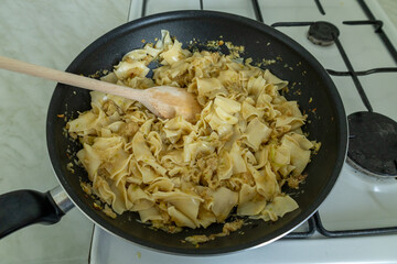 cabbage noodles mixed in a wok with a wooden spoon