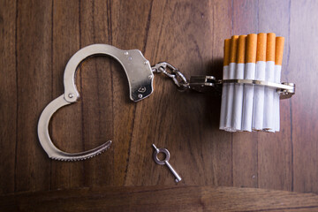 Cigarettes attached to a handcuff and hand, as in attached to your self and cant quit