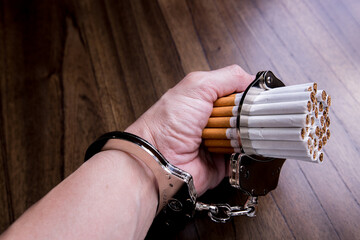 Cigarettes attached to a handcuff and hand, as in attached to your self and cant quit