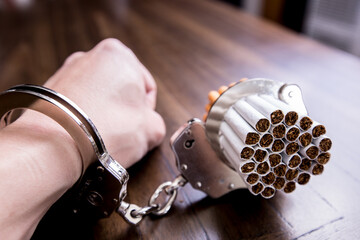 Cigarettes attached to a handcuff and hand, as in attached to your self and cant quit
