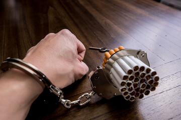 Cigarettes attached to a handcuff and hand, as in attached to your self and cant quit