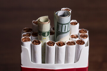 Cigarette concept inside a pack with money as in burning your money to buy drugs 