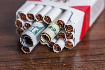 Cigarette concept inside a pack with money as in burning your money to buy drugs 