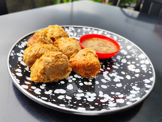 Tahu walik, tofu walik traditional Indonesian food, on a black table, aesthetic modern outdoor cafe menu, when the weather is cloudy.