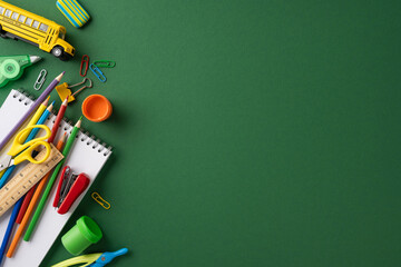 Colorful school supplies arranged artistically on a green background, symbolizing education,...