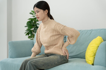 Obraz premium woman holding her lower back while and suffer from unbearable pain health and problems, chronic back pain, backache in office syndrome, scoliosis, herniated disc, muscle inflammation.
