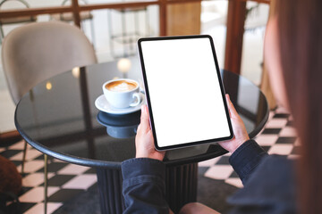 Mockup image of a woman holding digital tablet with blank white desktop screen in cafe