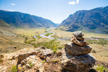 Stone cairn on mountain with view of Chulyshman valley and river in Altai Russia Symbol of hiking and nature exploration