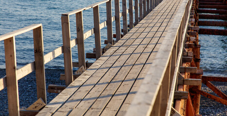 A wooden pier with a wooden walkway leading to the water