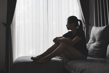 Sad and depressed woman sitting on sofa at home.Stop violence against women,  Domestic abuse victim. Suicide due to depression.
