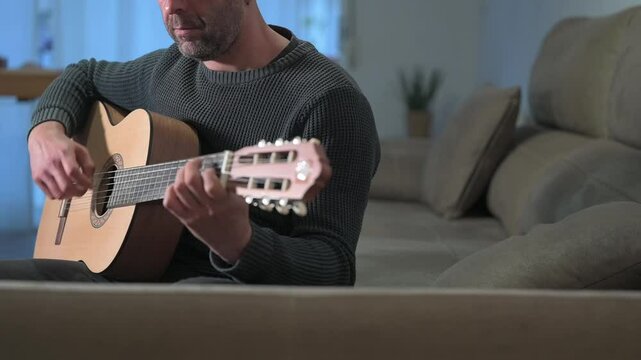 Musician playing acoustic guitar at home