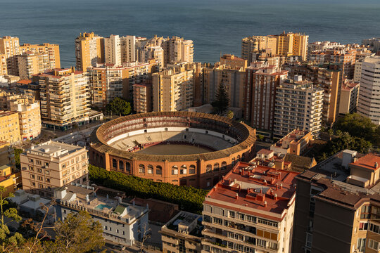 Cityscape aerial view of Malaga. Aerial view of a historic bullring surrounded by urban buildings and coastal scenery in a vibrant city landscape - Powered by Adobe