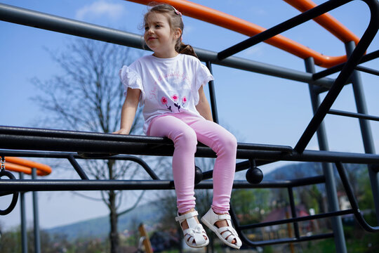 Little girl climbing on jungle gym in playground on a sunny day