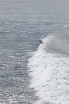 Minimal surfer riding white wave in blue ocean
