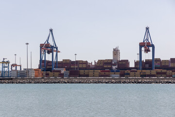 Container port with large cranes lifting cargo, surrounded by water, showcasing industrial shipping...