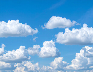 Obraz premium Fluffy white cumulus clouds drift across a vibrant blue sky on a sunny day, creating a peaceful and serene atmosphere.