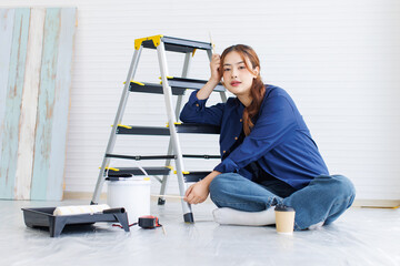 Asian young beautiful woman long curly hair wearing blue shirt jeans posing sitting back in ladder...