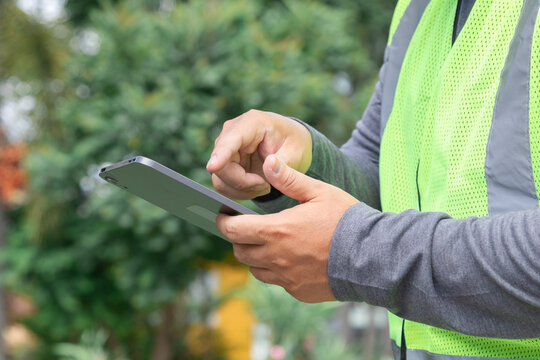 Asian overweight construction project foreman wearing white hard hat and reflective safety vest stand inspecting construction holding tablet and building plan, Inspect and explain work to workers.