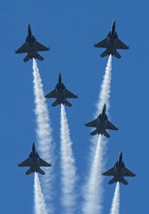 Photo of Six Fighter Jets in Formation with White Smoke Trail Against Blue Sky