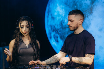 Two DJs Performing Together with Headphones and Equipment at a Stunning Music Event