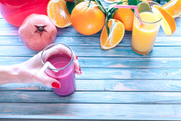 freshly squeezed pomegranate juice in a women's hand with oranges and pomegranate fruit