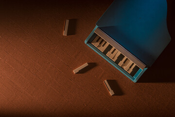 Blue toy piano with three broken keys on the floor. The piano is not in good condition and the wood pieces are scattered around it. Metaphor of hard childhood and kids troubles. 3d render