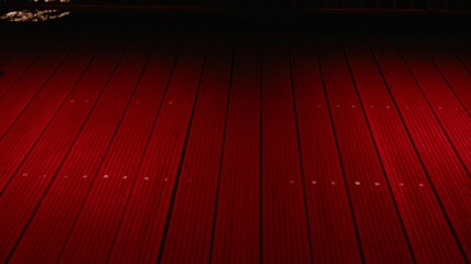 Women in long dresses walking gracefully across red wooden flooring, creating dramatic atmosphere with elegant movement and mysterious nighttime ambiance. Girls feet slide across illuminated red floor