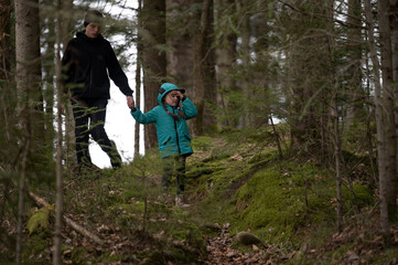 Obraz premium Exploring the serene forest path as a child and adult bond over nature and adventure during a quiet, misty afternoon in the woods