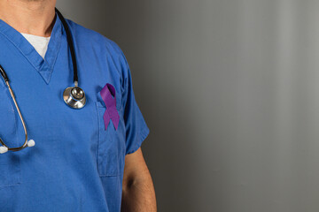 Medical professional wearing blue scrubs with purple ribbon for awareness