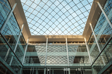 An interior view of a contemporary building’s atrium, featuring a symmetrical glass roof...