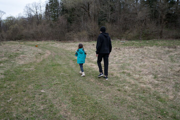 Joyful exploration of a child and adult together on a tranquil trail in nature, surrounded by trees...