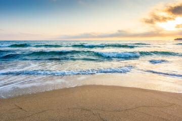empty beach in the forenoon. wet seashore. beautiful landscape at the black sea. waves washing the sand on the shore. clouds glowing in morning light. calm summer vacation and travel destination