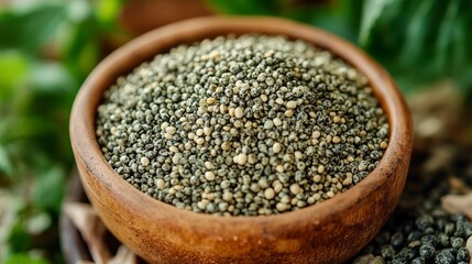 Wood bowl of small grains surrounded by green leaves on a wooden table