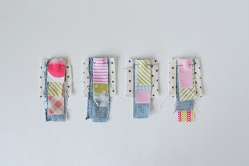 Tiny fabric scraps with sewing pins on white background