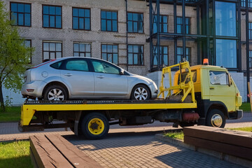 A broken-down car on a tow truck. A tow truck takes away a broken-down car.