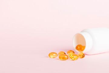 Soft gels pills with Omega-3 oil spilling out of pill bottle close-up. Gel capsules bottle white...