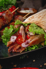 Appetizing grilled skewers with shawarma wrap stuffed with juicy meat, lettuce, cherry tomatoes and red onion. A perfect meal for food ads or menus