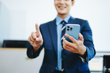 Smiling businessman in suit holds smartphone while gesturing to interact, symbolizing fintech, mobile ap