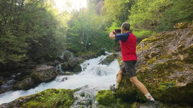 Man exploring waterfall at sunset in Badain, Ainsa, Huesca, Aragonese Pyrenees, 4K video of natural adventure with warm light and river landscape between rocks, hiking and nature tourism.
