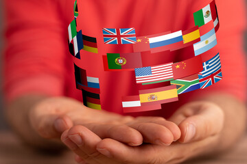 Image of hands gently holding a swirling array of international flags, symbolizing global unity and...