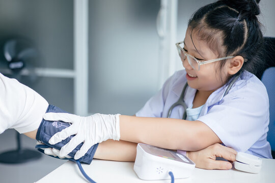 Girl in doctor's uniform examining a patient at a table, Concept Education - Powered by Adobe