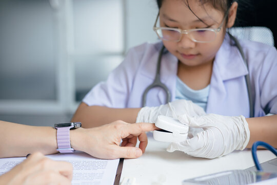 Girl in doctor's uniform examining a patient at a table, Concept Education