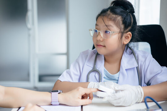 Girl in doctor's uniform examining a patient at a table, Concept Education - Powered by Adobe