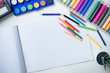 Top View of Colored Pencils, Sketchbook and Drawing Supplies on White Table